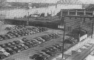 Site of the new plant will be this lot formerly occupied by an oil refinery works.  Purchased in 1941, the lot was used by A-C for outdoor storage and as a parking lot for employes' cars. In the background is the Ohio River.